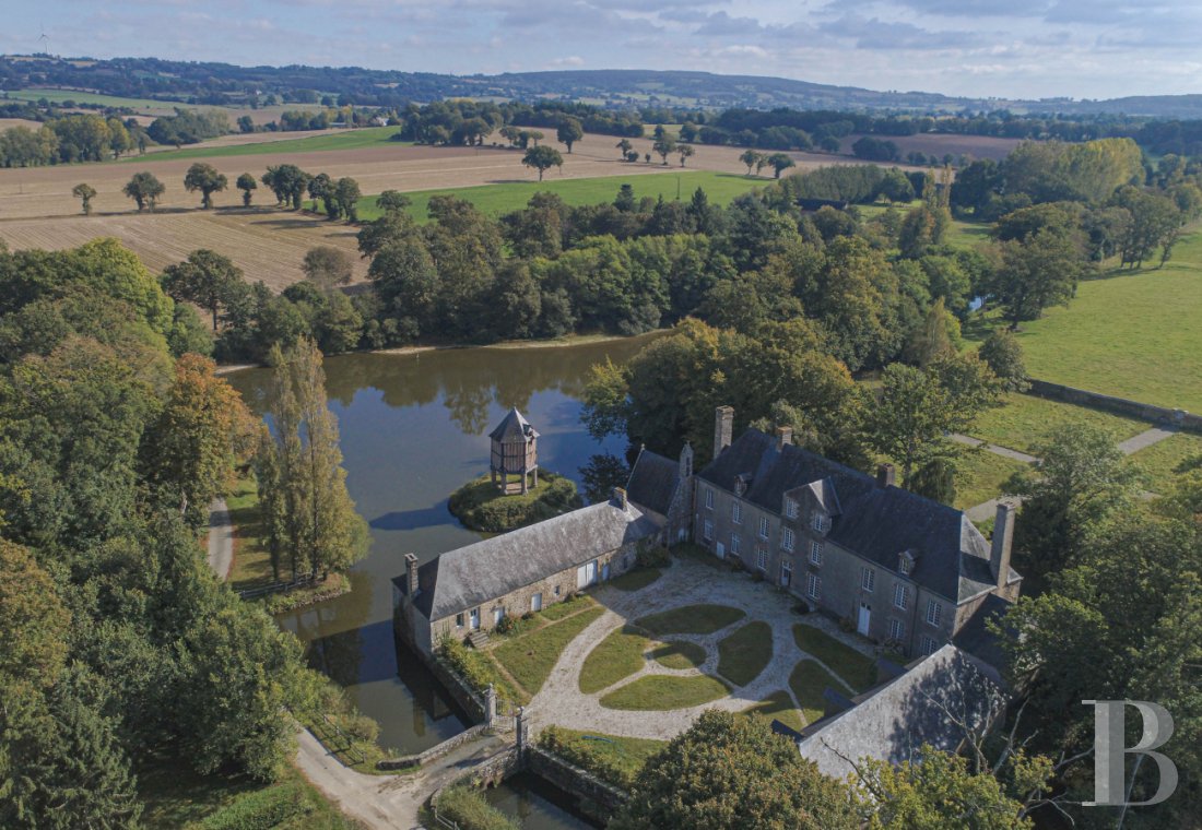 En Mayenne, au nord de la ville éponyme, un château du 17e siècle ceinturé de douves en eau - photo  n°1