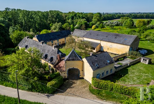 En Flandre, une ferme traditionnelle en brique blonde et ses dépendances autour de la cour pavée.